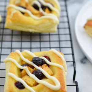 Peach Blueberry Tart- This easy fruit tart is the perfect use of summer’s juicy blueberries and peaches. The tart is made out of Puff Pastry and then topped with seasoned blueberries and peaches with a vanilla cream cheese drizzle. www.domesticdee.com